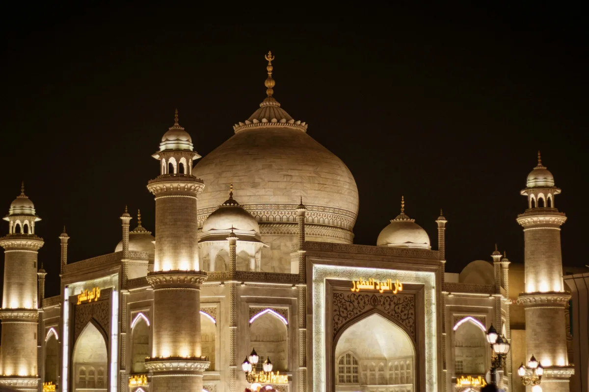 Ornate pavilion with tall towers lit up at night at Global Village Dubai